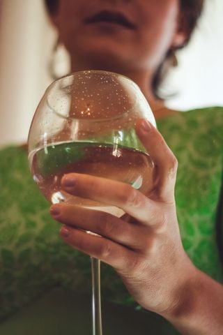 Holding wine glass closeup with green dress, delicate hand detail and soft portrait bokeh