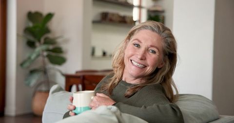 Relaxed Mature Woman Smiling with Coffee at Cozy Home
