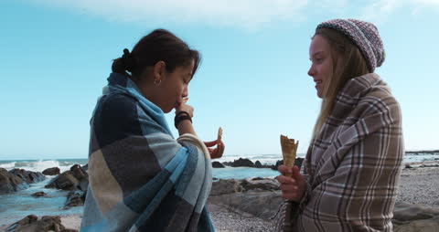 Two Friends Eating Ice Cream on a Chilly Beach