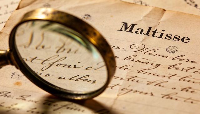Brass magnifier enlarging handwritten maltisse manuscript on aged parchment
