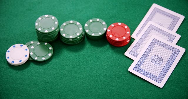 Poker chips in neat stacks and playing cards placed on green felt table. Useful for articles, blogs, websites about casino games, gambling strategies, online poker tutorials, or gaming promotions.