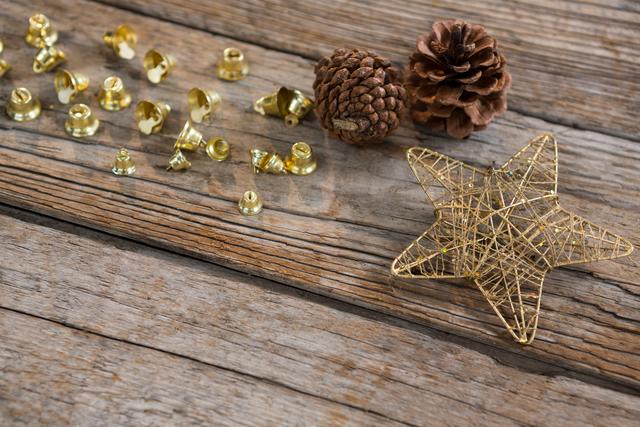 Christmas decorations with gold bells, pine cones, and a woven star on a rustic wooden background. Ideal for holiday greeting cards, festive social media posts, Christmas advertisements, winter-themed print materials, and seasonal home decor inspiration.
