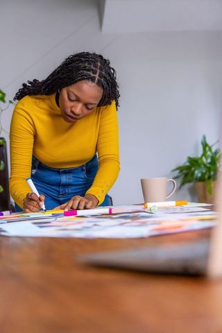 African american woman sketching at loft studio, planning design with markers and swatches