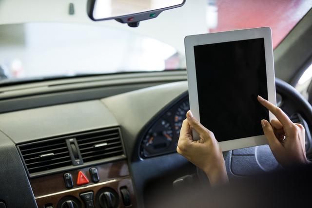 Mechanic using digital tablet in car captures modern automotive diagnostics and maintenance process. Useful for articles on car technology, repair services, and advancements in the automotive industry.