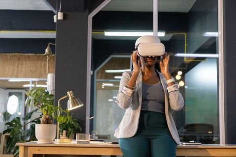 African american woman adjusting vr headset sitting on office desk in coworking space