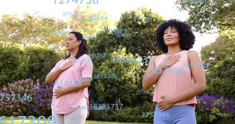 Practicing mindful breathing in sunlit garden, two women doing breathwork for wellness