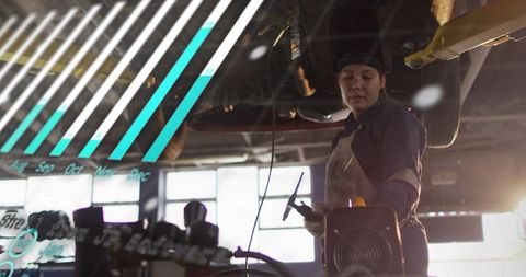 Female automotive technician diagnosing undercarriage using diagnostic probe under raised car