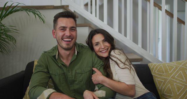 Portrait of caucasian couple sitting on sofa and smiling. lifestyle, leisure, spending time at home.