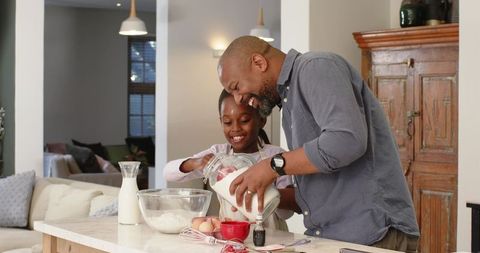 Father and Daughter Mixing Batter in Modern Kitchen