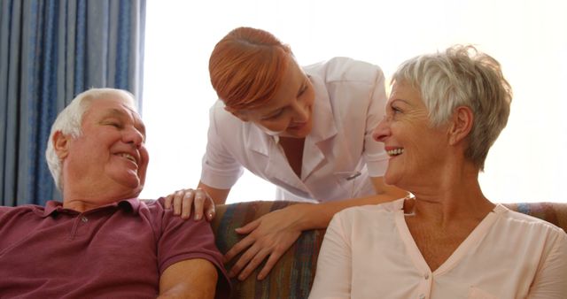 Senior couple and a nurse sitting together indoors. Nurse is providing assistance and support while both seniors are smiling and feeling happy. Perfect for use in healthcare, elderly care services, and lifestyle articles related to aging, senior support, and nursing care.