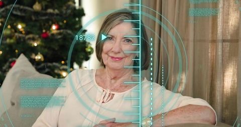 Smiling senior woman relaxing on sofa with christmas tree and futuristic hud overlay