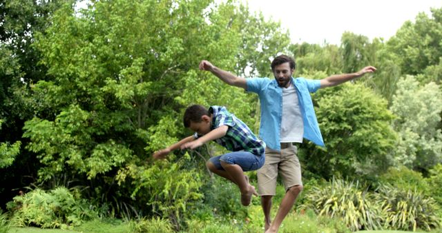 Adult male and young boy enjoy outdoor activities by jumping energetically amidst lush green surroundings. This image highlights family bonding, outdoor fun, and active play, making it ideal for parenting blogs, family-oriented promotions, nature activities advertisements, and lifestyle articles focused on health and wellness.