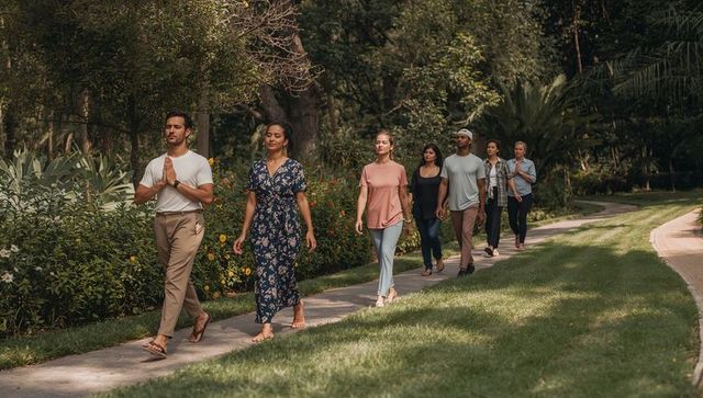 Diverse group walking mindful stroll along lush garden path promoting wellness