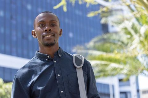 African american professional standing outdoors with shoulder bag in modern urban office area