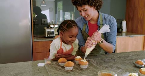 Mother and daughter joyfully decorating homemade cupcakes
