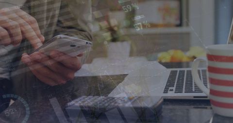 Businessman Analyzing Financial Data on Smartphone and Laptop at Home