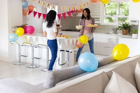 African american mother and teen daughter decorating kitchen for birthday celebration