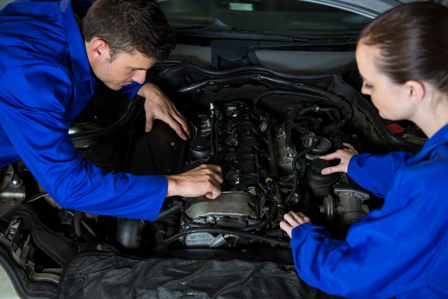 Mechanics examining car engine at repair garage