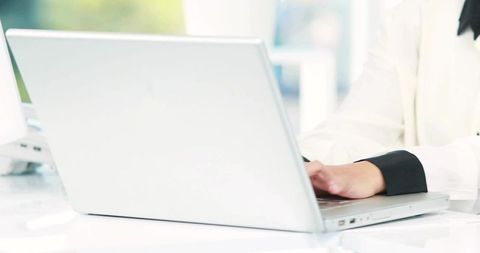 Businesswoman Typing on Silver Laptop in Bright Workspace
