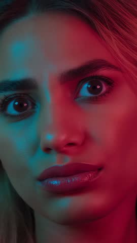 Woman Turning Shock into Thought Touching Face in Teal Magenta Neon Light Vertical Video