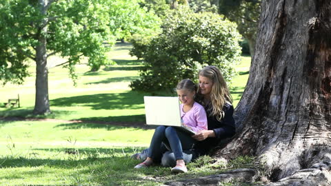 Mother and Daughter Enjoying a Book Under a Large Tree
