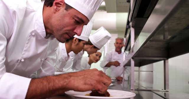 Chefs are focusing intently on delicately plating their dishes, showcasing attention to detail and culinary skills. This image is suitable for illustrating culinary competitions, cooking classes, teamwork in a kitchen, or modern culinary techniques.