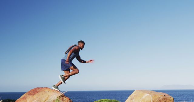 African american man exercising outdoors jumping on rocks in countryside on a mountain. fitness training and healthy outdoor lifestyle.