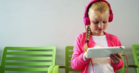 Young Girl Engaged with Tablet and Pink Headphones