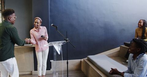 Engaging public speaker interacting with diverse audience in modern auditorium