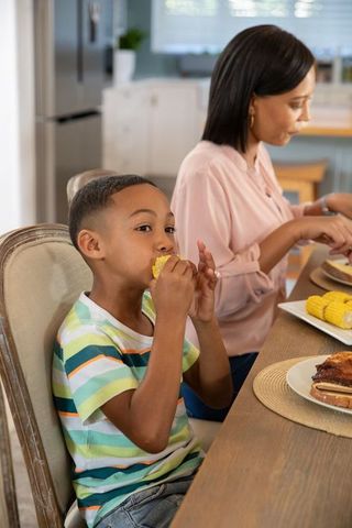 Mother and Son Enjoying Quality Time Eating Corn in the Kitchen