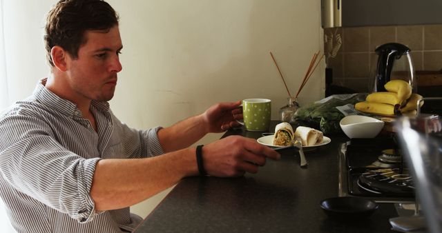 Man Having Breakfast with Wrap and Coffee at Kitchen Counter - Download Free Stock Images Pikwizard.com