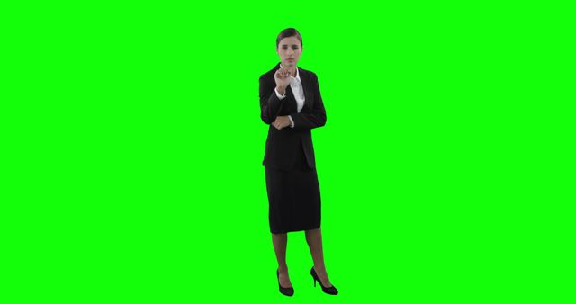 Professional businesswoman in a suit pointing at the camera against a green screen background. Ideal for business marketing, corporate presentations, and professional websites. The green screen allows for easy background replacement for various creative projects.