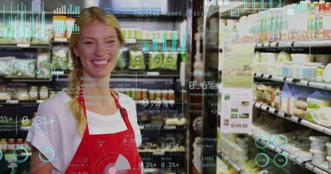 Smiling grocery clerk wearing red apron using augmented reality analytics in aisle