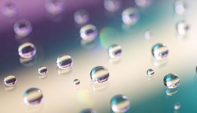 Iridescent water droplets reflecting pastel gradient on glass surface macro bokeh