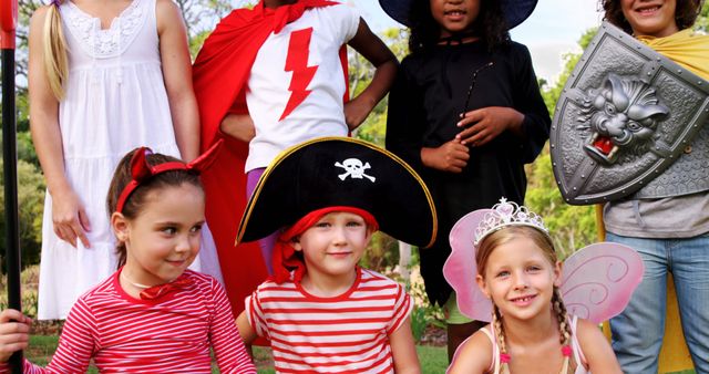 A group of young children dressed in various costumes, including a pirate and a fairy, are enjoying a costume party outdoors, with copy space. Their playful attire and joyful expressions capture the spirit of childhood imagination and festive celebrations.