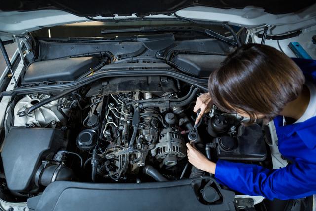 Female mechanic is servicing car engine in repair garage. Perfect for automotive industry content, workshop advertisements, car repair service promotions, and illustrations of gender diversity in technical professions.
