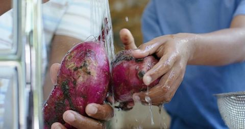 African american father and son rinsing purple yams at kitchen sink