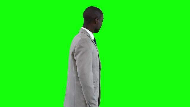 A businessman in a formal suit is gesturing as if presenting information against a green screen background. This can be used for corporate presentations, educational videos, or promotional content where a custom background will be added.