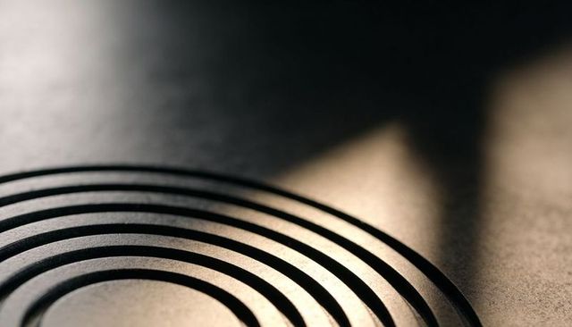 Concentric metal groove rings with warm highlight and deep shadow, minimal abstract design