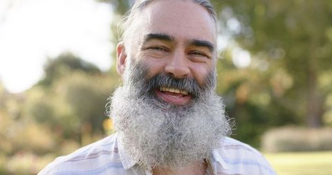 Smiling bearded man relaxing in outdoor park on sunny day