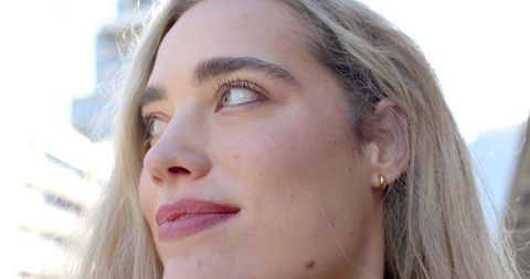Closeup young woman gazing left wearing gold hoop earring urban backlit portrait