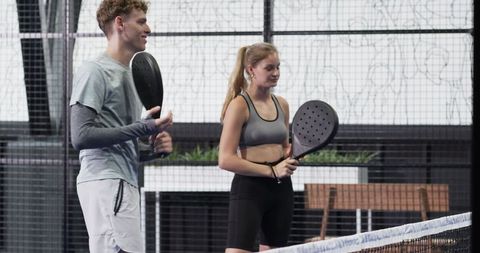 Young adults enjoying padel with rackets on modern court