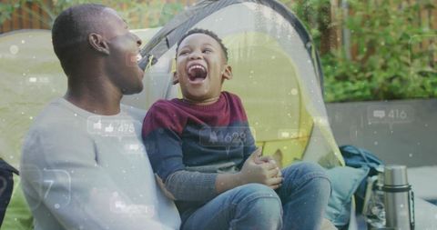 African american father laughing with son while backyard camping and bonding outdoors