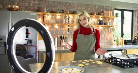 Home baker filming cookie decorating tutorial with ring light and smartphone