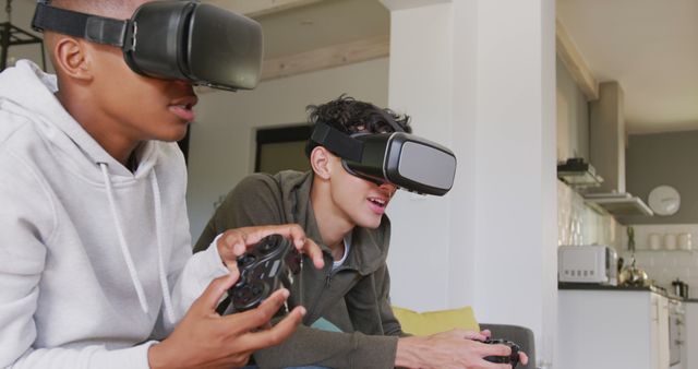 Two teenagers engrossed in virtual reality gaming. They wear VR headsets and hold game controllers. The background shows a contemporary living room with furniture and decor. Ideal for articles on technology, modern gaming trends, immersive experiences, and youth activities.
