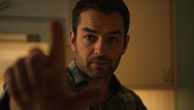 Middle-aged man staring and reaching forward in warm moody kitchen closeup