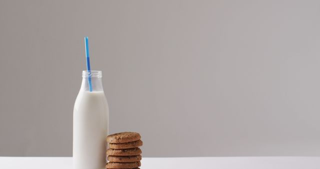 Simple, minimalist image displaying a classic snack with a glass bottle of milk and a stack of cookies. Ideal for use in advertising, social media, and food blogs to evoke a sense of nostalgia, comfort, and simplicity in meal choices. Useful for promoting dairy products, healthy snacks, or breakfast ideas.