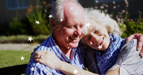 Senior couple embracing joyfully on garden bench