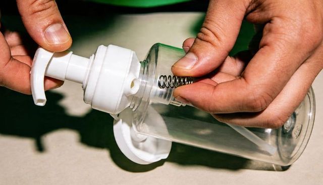 Hands assembling clear foaming pump dispenser with spring close-up repair macro