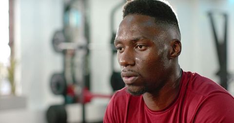 Sweaty african american athlete catching breath after intense weightlifting session